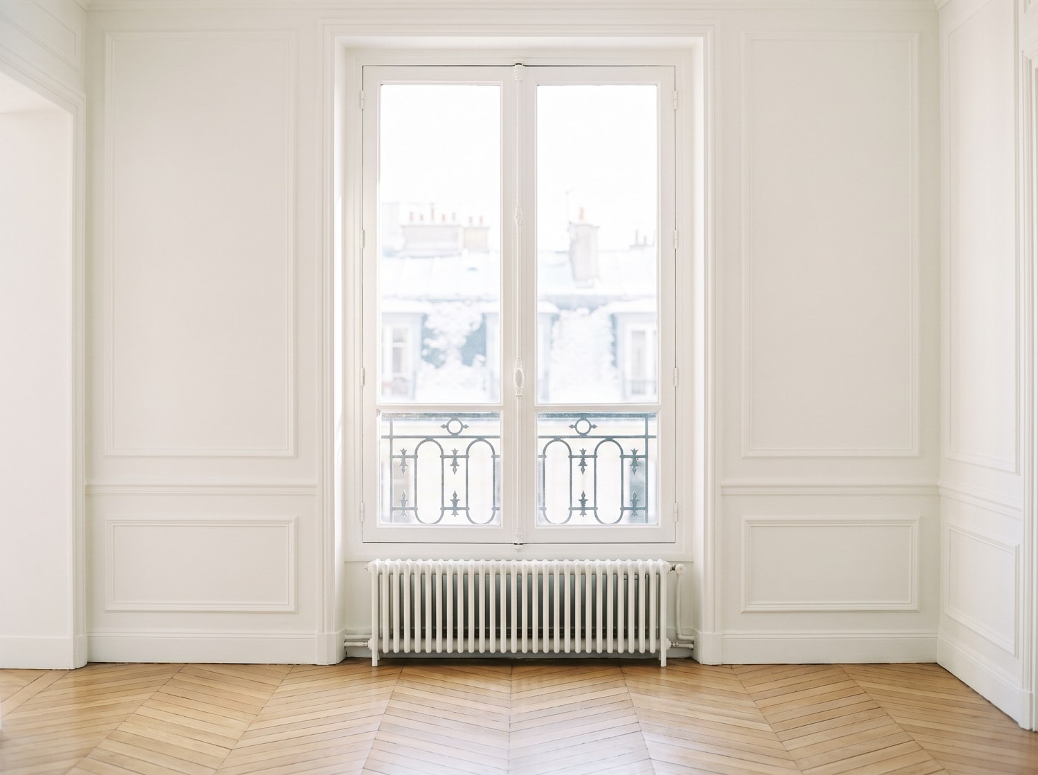 Une fenêtre parisienne et son radiateur en fonte, dans une pièce vide